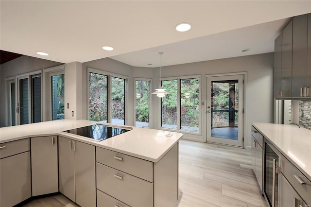 kitchen featuring gray cabinetry, black electric stovetop, hanging light fixtures, wine cooler, and light hardwood / wood-style floors