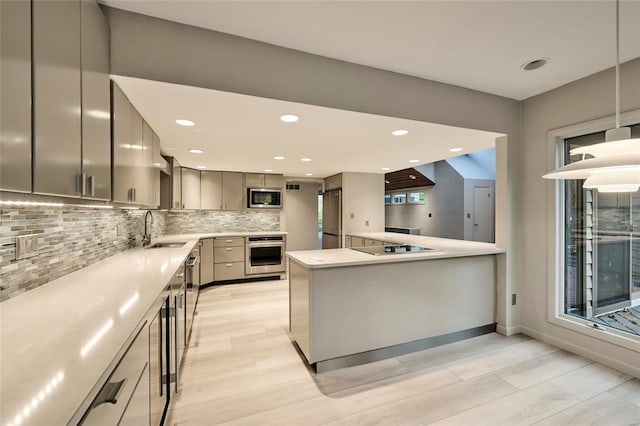 kitchen featuring gray cabinetry, sink, hanging light fixtures, decorative backsplash, and appliances with stainless steel finishes