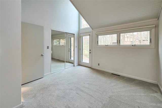 unfurnished room with a healthy amount of sunlight, lofted ceiling, and light carpet