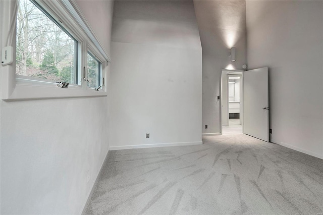 carpeted spare room featuring a high ceiling