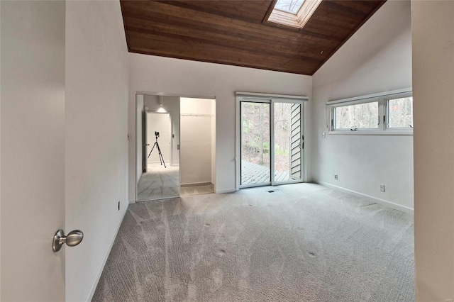 carpeted empty room featuring lofted ceiling with skylight and wood ceiling