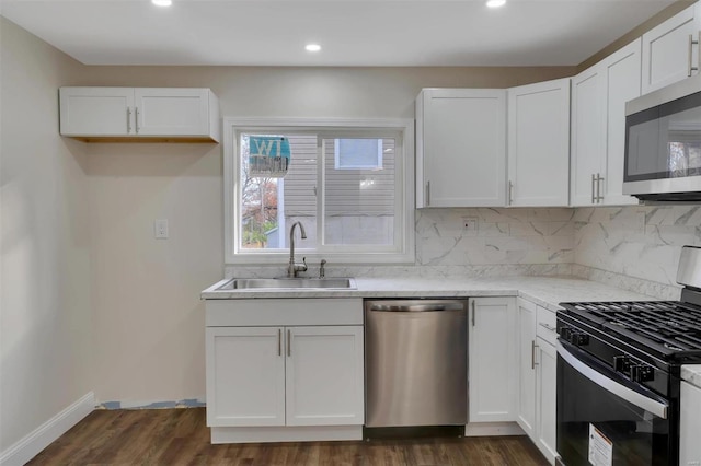 kitchen featuring dark wood-type flooring, sink, decorative backsplash, appliances with stainless steel finishes, and white cabinetry