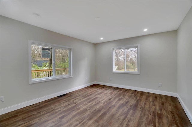 empty room featuring dark hardwood / wood-style flooring and a wealth of natural light