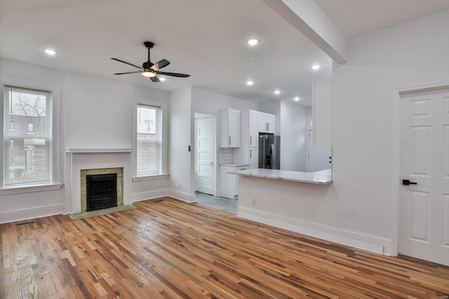 unfurnished living room with ceiling fan, light hardwood / wood-style floors, and a healthy amount of sunlight