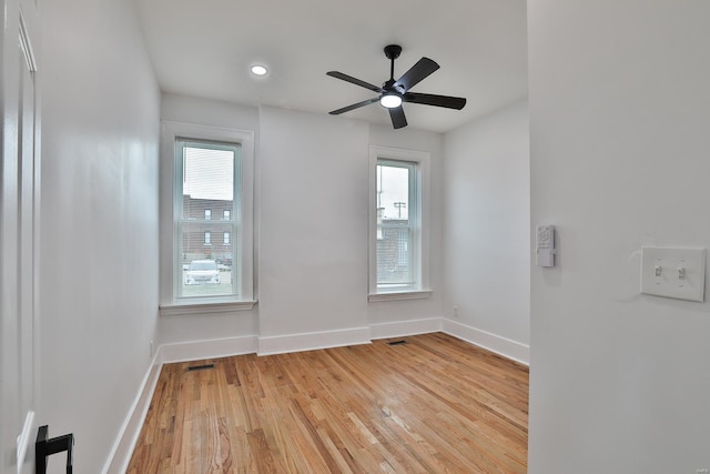 spare room featuring a healthy amount of sunlight, ceiling fan, and light hardwood / wood-style flooring