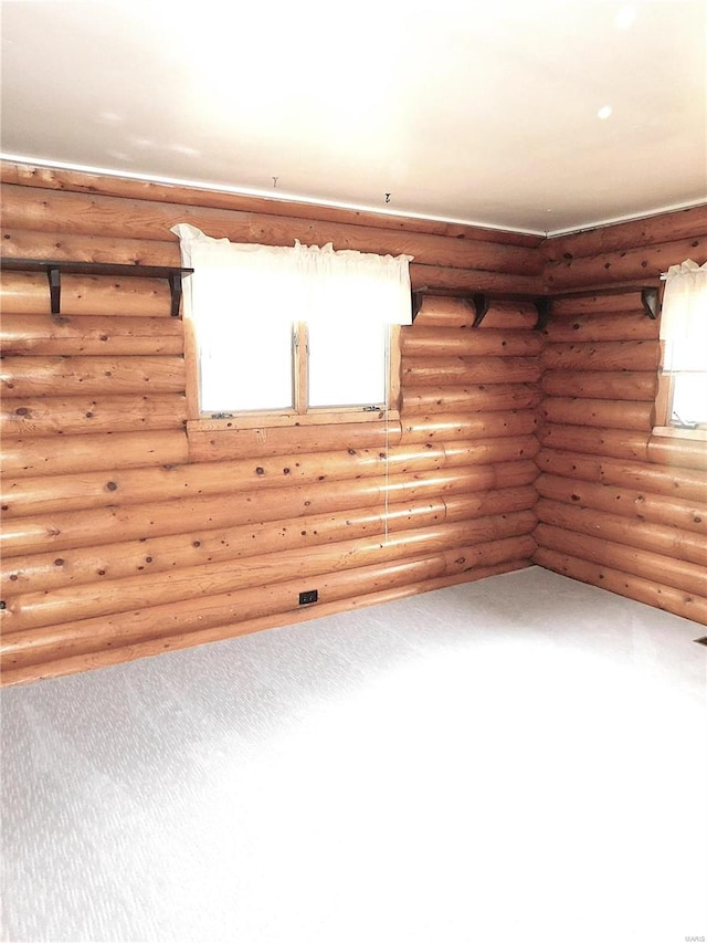 carpeted spare room with log walls