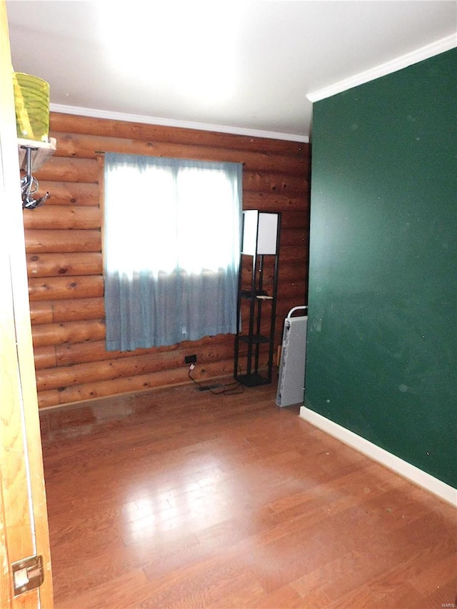 unfurnished room with log walls, hardwood / wood-style flooring, and ornamental molding