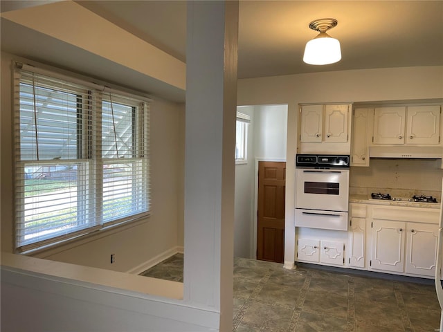 kitchen with white appliances, white cabinets, a wealth of natural light, and tasteful backsplash