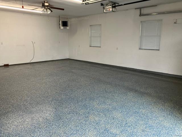 garage with a wall mounted air conditioner, ceiling fan, and a garage door opener