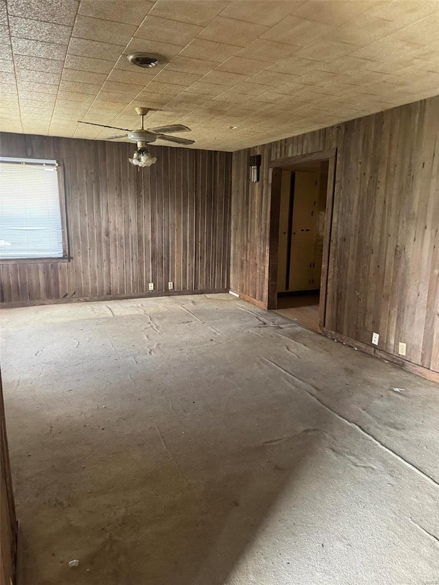 unfurnished room with ceiling fan and wooden walls