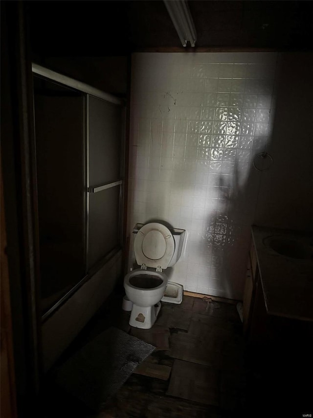 bathroom with toilet, tile patterned floors, and tile walls