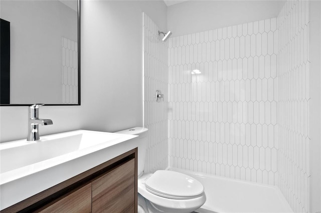 bathroom with tiled shower, vanity, and toilet