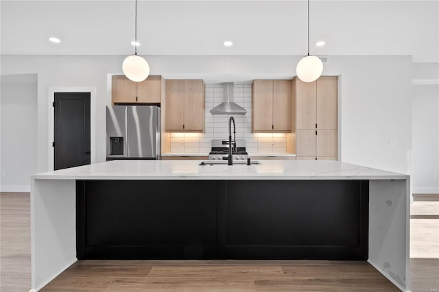 kitchen featuring light stone counters, wall chimney exhaust hood, decorative light fixtures, and appliances with stainless steel finishes