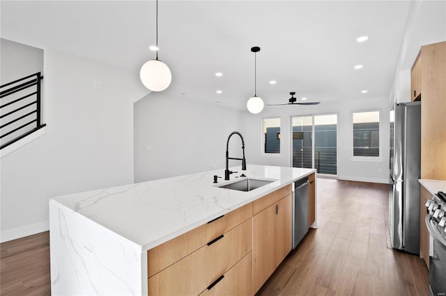 kitchen featuring sink, hanging light fixtures, dark wood-type flooring, a large island with sink, and appliances with stainless steel finishes