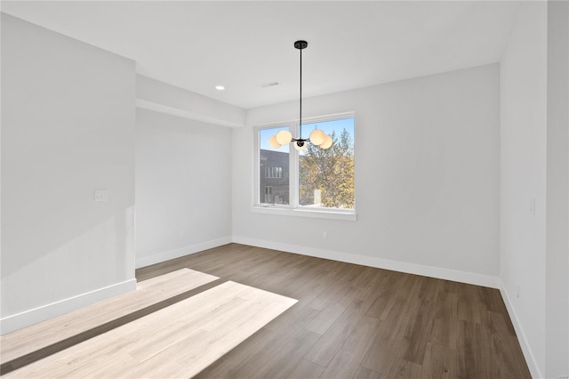 unfurnished dining area with a chandelier and wood-type flooring