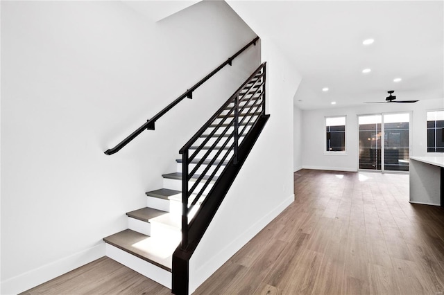 staircase featuring wood-type flooring and ceiling fan