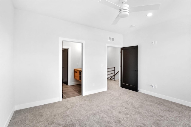 unfurnished bedroom with ceiling fan, light colored carpet, and ensuite bathroom