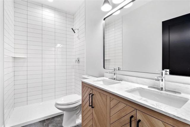 bathroom with tile patterned floors, vanity, toilet, and a tile shower