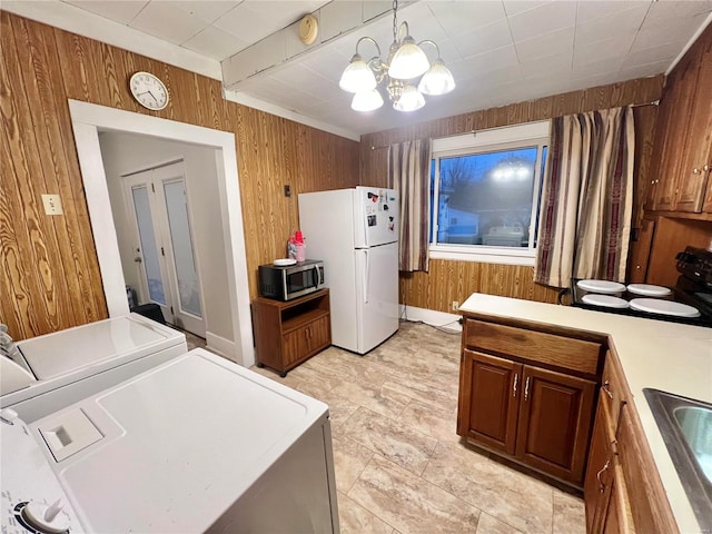 kitchen featuring a chandelier, pendant lighting, white fridge, and wood walls