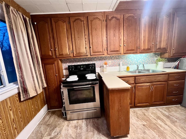 kitchen featuring decorative backsplash, electric range, sink, and wooden walls