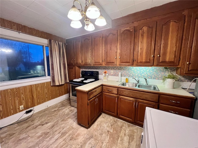 kitchen with a notable chandelier, sink, wooden walls, electric range, and decorative light fixtures