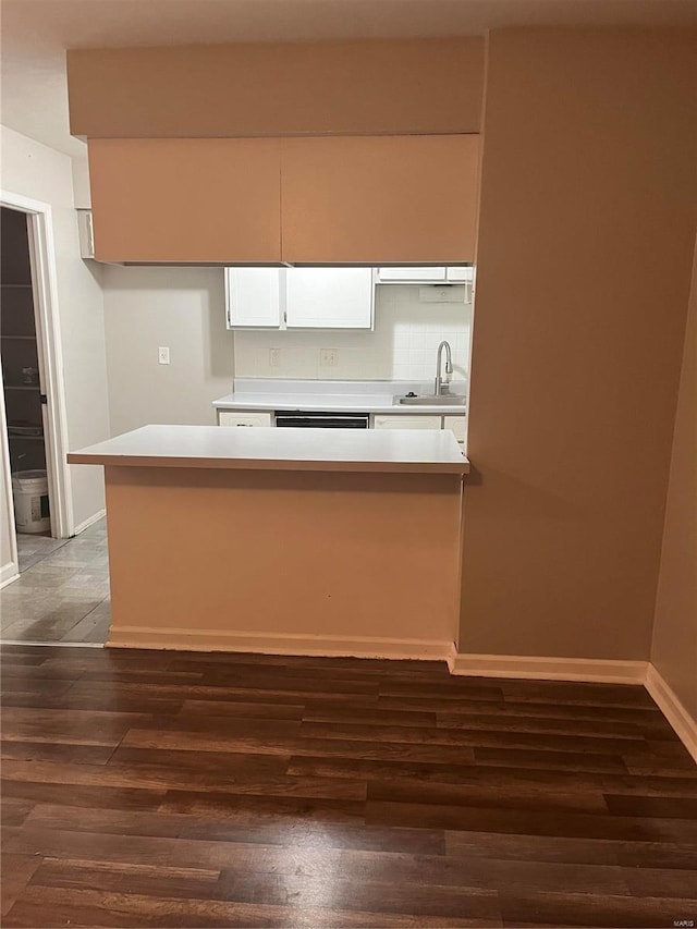 kitchen featuring kitchen peninsula, dark hardwood / wood-style flooring, sink, white cabinets, and black dishwasher