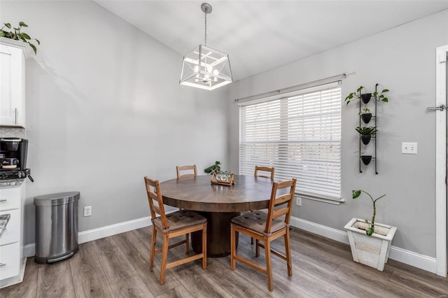 dining room with hardwood / wood-style floors, a notable chandelier, and vaulted ceiling