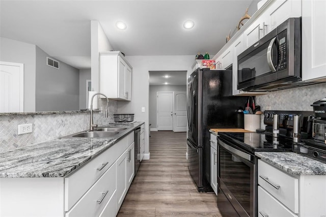 kitchen with tasteful backsplash, stainless steel appliances, sink, hardwood / wood-style flooring, and white cabinets