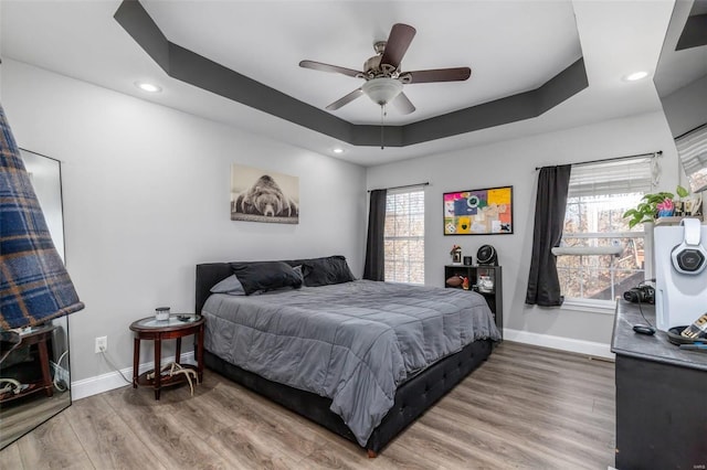 bedroom with a raised ceiling, ceiling fan, and hardwood / wood-style flooring