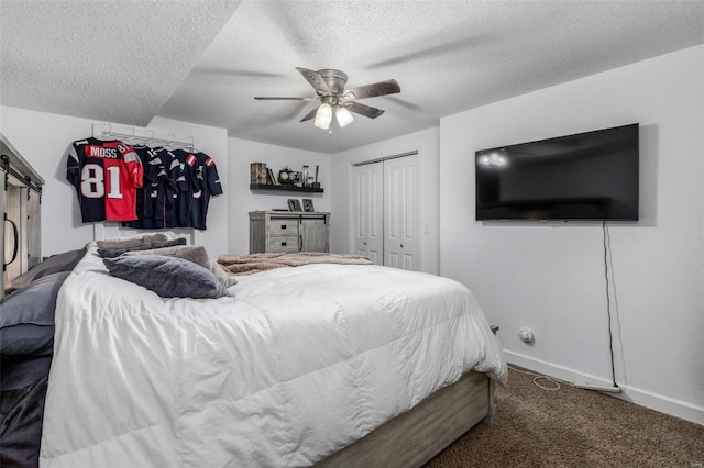 carpeted bedroom with ceiling fan, a barn door, and a textured ceiling