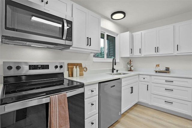 kitchen featuring white cabinetry, sink, appliances with stainless steel finishes, and light hardwood / wood-style flooring