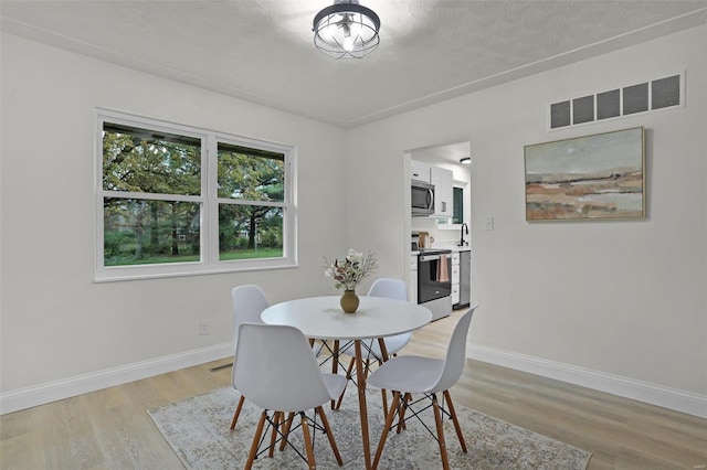 dining room with a textured ceiling and light wood-type flooring