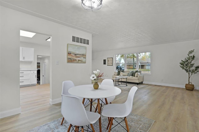 dining room with a textured ceiling and light hardwood / wood-style floors