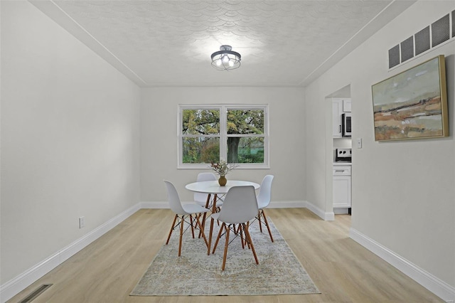 unfurnished dining area featuring light hardwood / wood-style floors and a textured ceiling