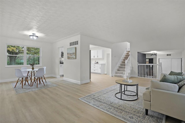 living room with light wood-type flooring and a textured ceiling