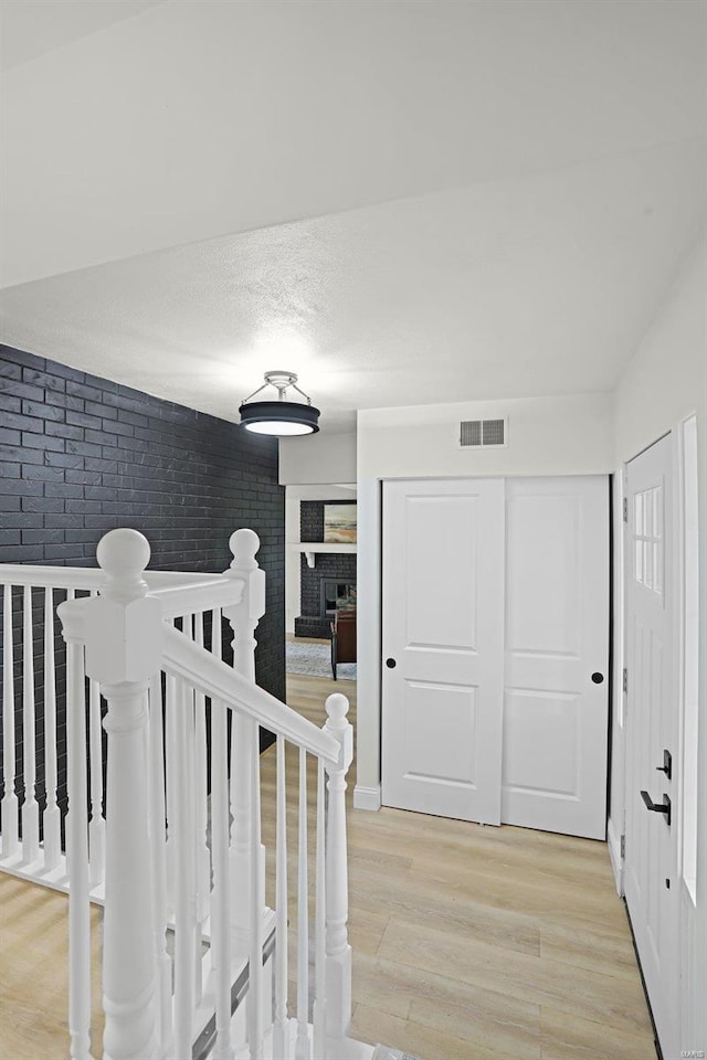 hallway with brick wall and light hardwood / wood-style flooring