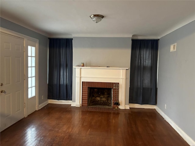 unfurnished living room featuring a fireplace, a wealth of natural light, and dark wood-type flooring