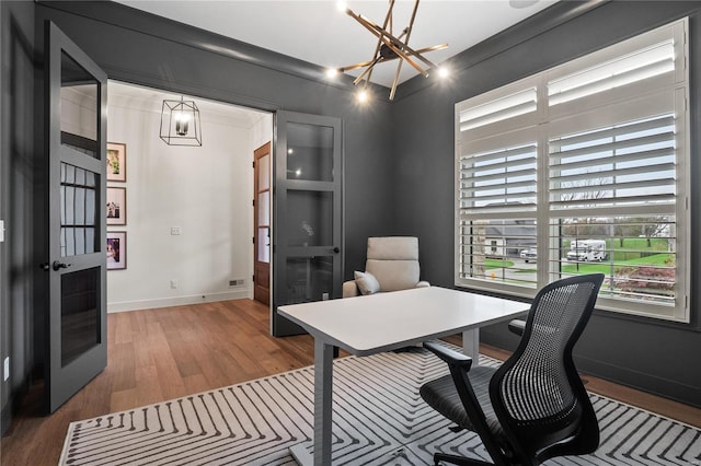 office area featuring wood-type flooring, french doors, crown molding, and an inviting chandelier