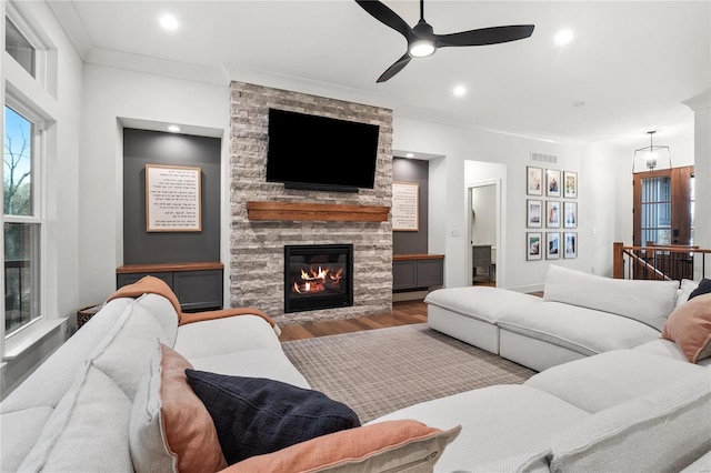 living room with hardwood / wood-style flooring, ceiling fan, crown molding, and a fireplace