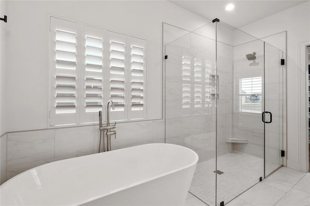 bathroom featuring tile patterned floors, a wealth of natural light, plus walk in shower, and tile walls