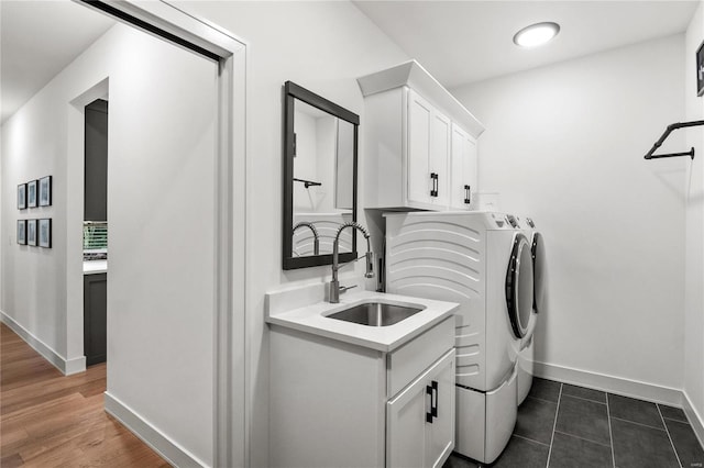 laundry area featuring separate washer and dryer, dark hardwood / wood-style flooring, cabinets, and sink