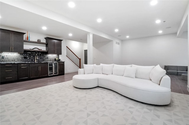 living room with light hardwood / wood-style floors, sink, and wine cooler