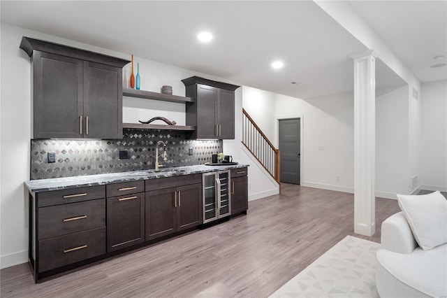 kitchen with tasteful backsplash, dark brown cabinetry, sink, and light hardwood / wood-style flooring