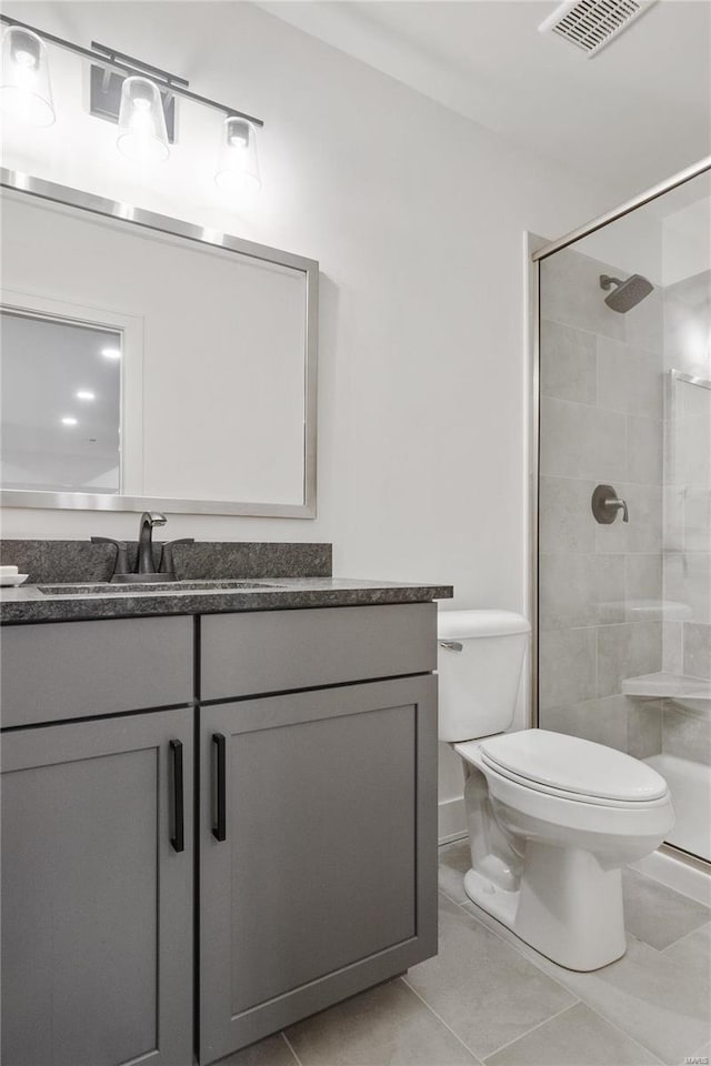 bathroom featuring a tile shower, tile patterned floors, vanity, and toilet