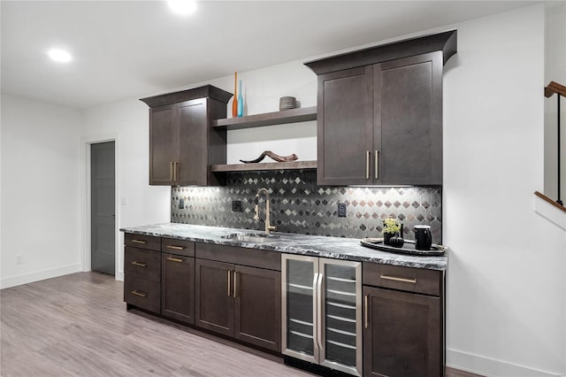 kitchen with sink, wine cooler, light hardwood / wood-style flooring, tasteful backsplash, and dark brown cabinetry