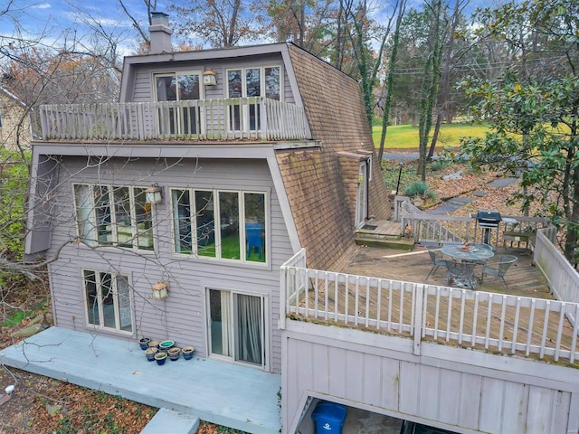 rear view of property featuring a balcony and a deck