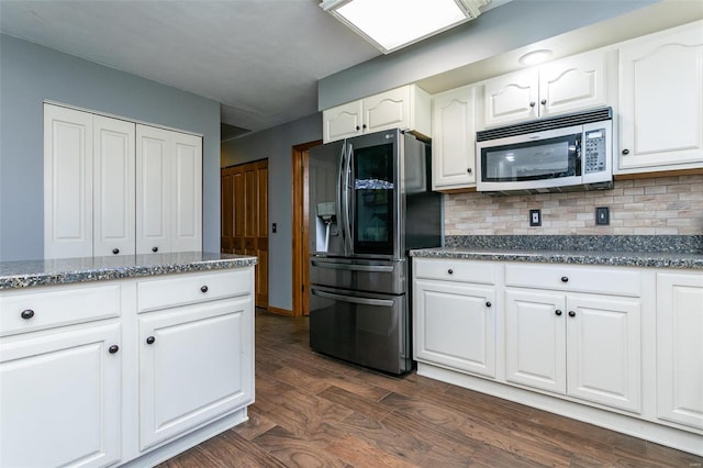 kitchen with dark hardwood / wood-style flooring, backsplash, dark stone counters, stainless steel appliances, and white cabinets