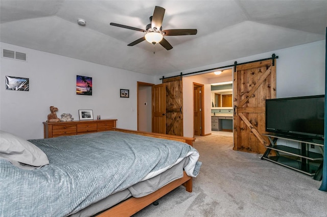 bedroom featuring ceiling fan, a barn door, ensuite bathroom, lofted ceiling, and light carpet