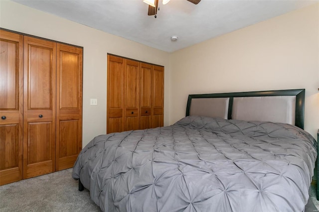 bedroom with multiple closets, ceiling fan, and light carpet