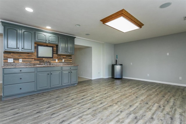 kitchen featuring light wood-type flooring, tasteful backsplash, and sink